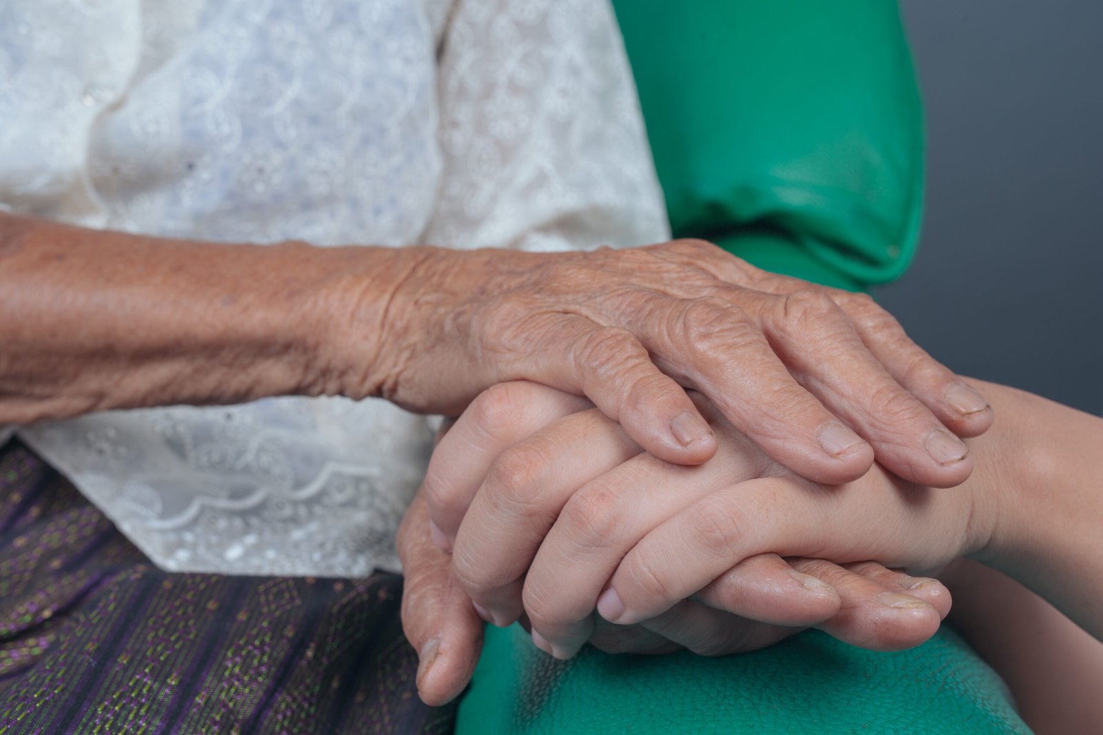 Young woman holding an elderly woman's hand.